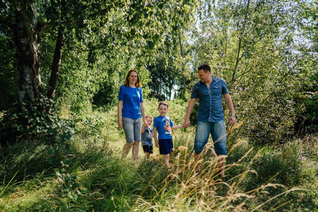 Familie mit zwei Kindern steht im hohen Gras am Waldrand – Sabrina Dötzl Fotografie Hollabrunn