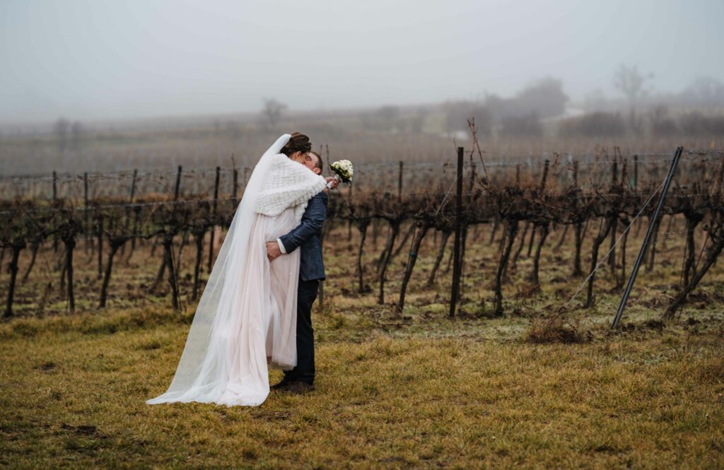 Brautpaar küsst sich im winterlichen Weinberg im Nebel – Sabrina Dötzl Fotografie Hollabrunn
