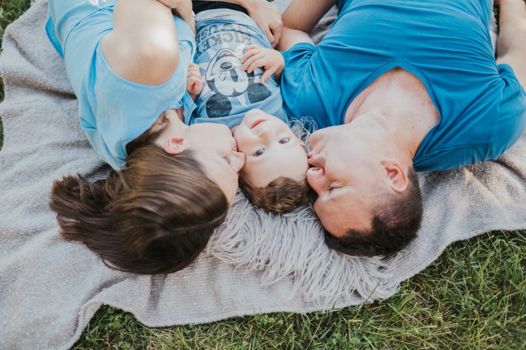 Familie liegt Kopf an Kopf mit Baby auf einer Decke – Sabrina Dötzl Fotografie Hollabrunn