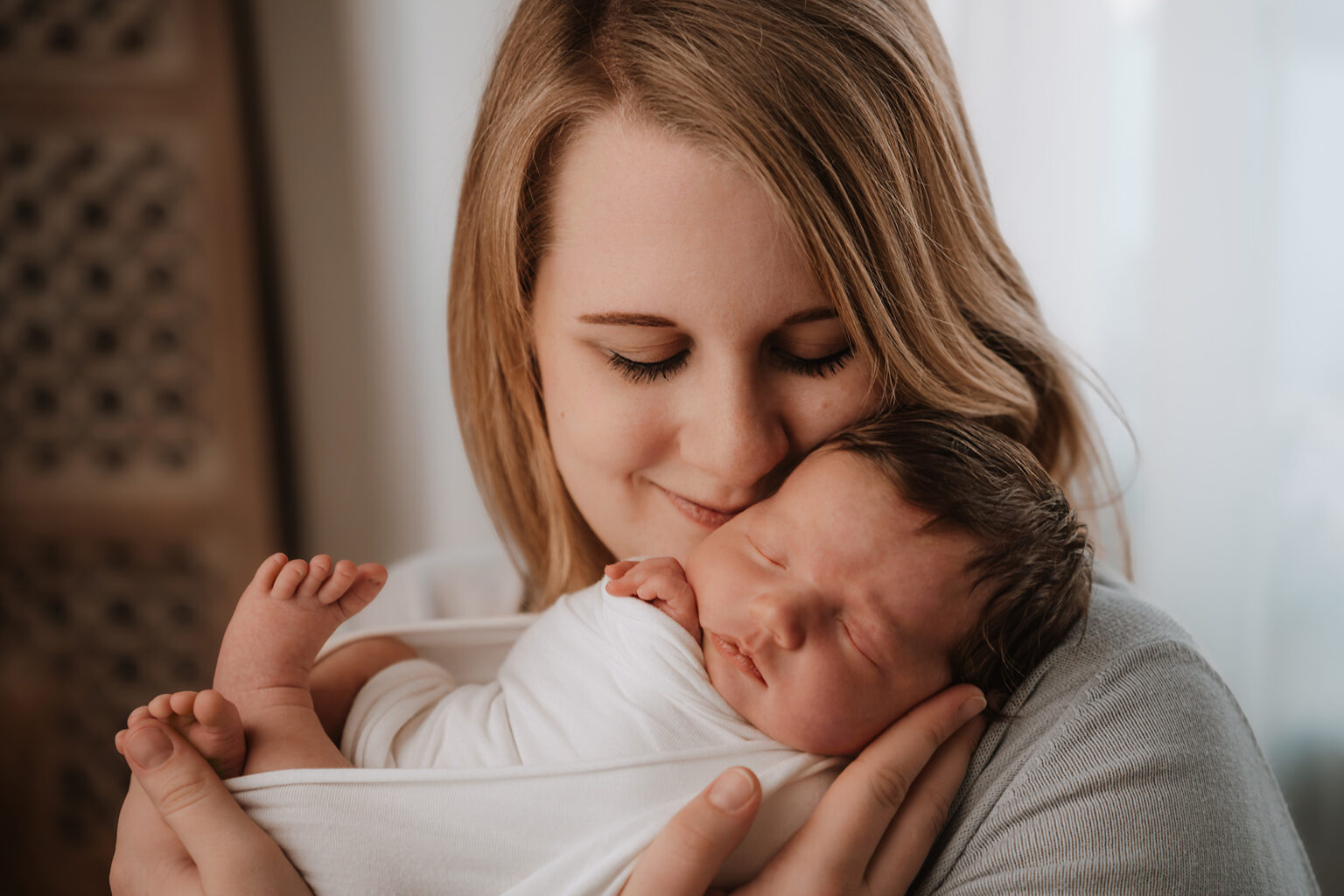 Mama hält ihr schlafendes Neugeborenes liebevoll im Arm