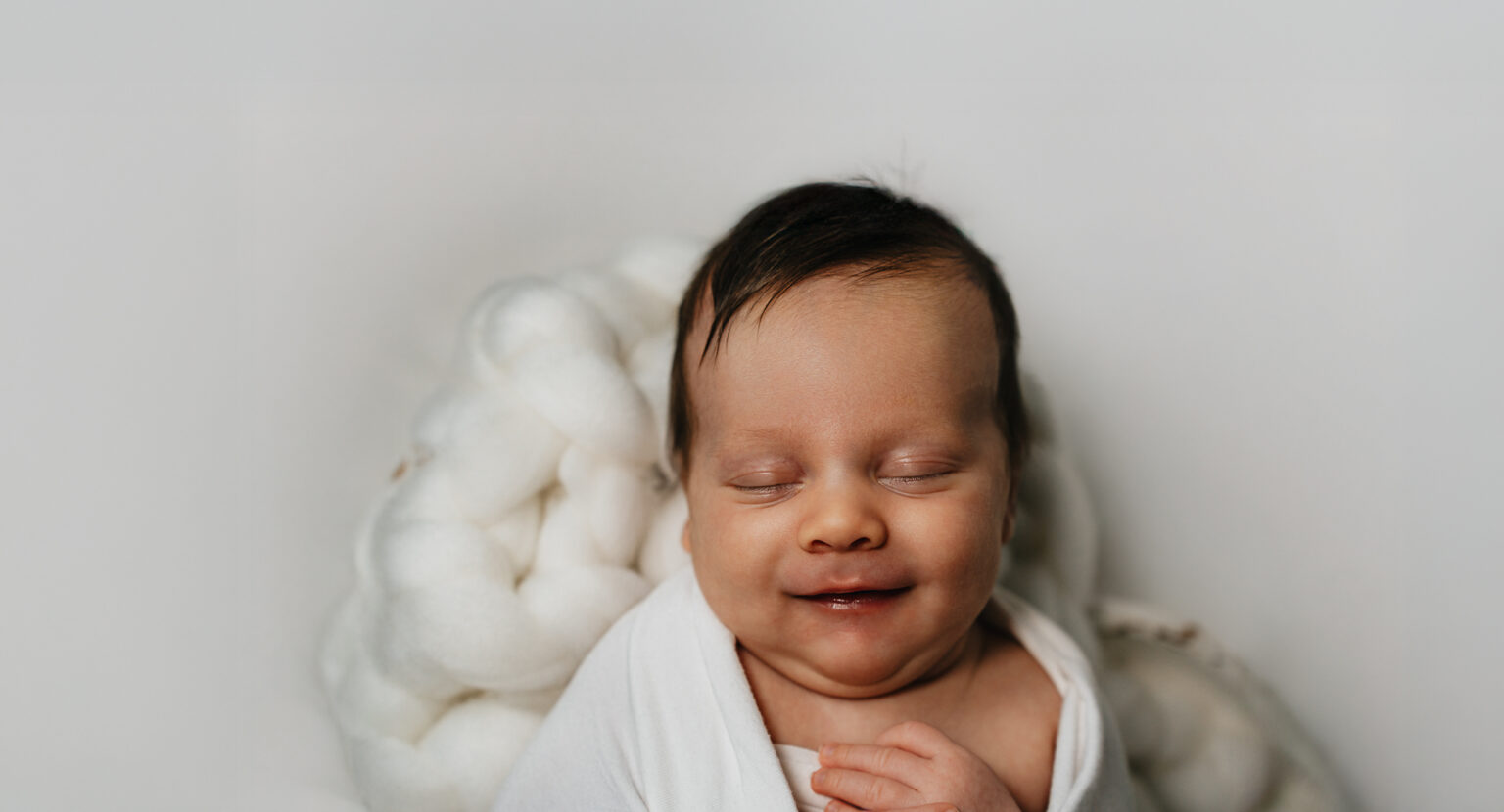 Neugeborenes Baby lächelt im Schlaf auf einer weichen Decke