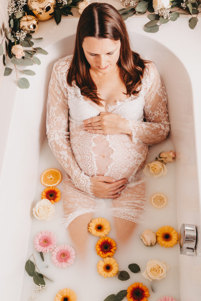 Schwangere liegt im Milchbad mit bunten Blüten, Babybauchshooting von oben – Sabrina Dötzl Fotografie Hollabrunn