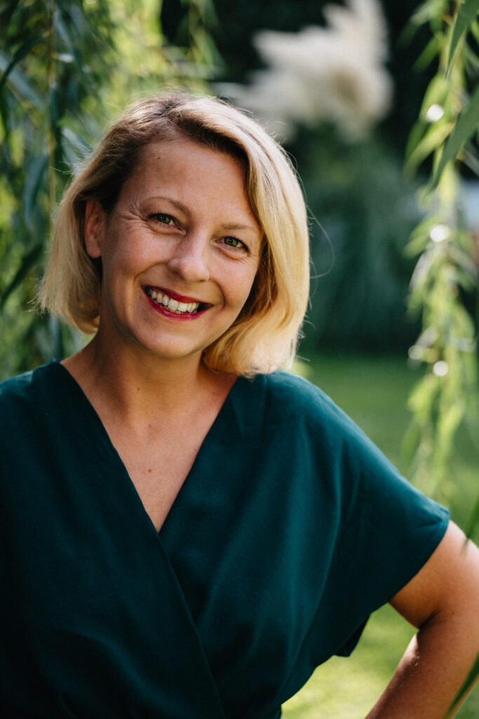 Fotografin Sabrina Dötzl lacht herzlich in die Kamera, Porträt im Grünen – Sabrina Dötzl Fotografie Hollabrunn