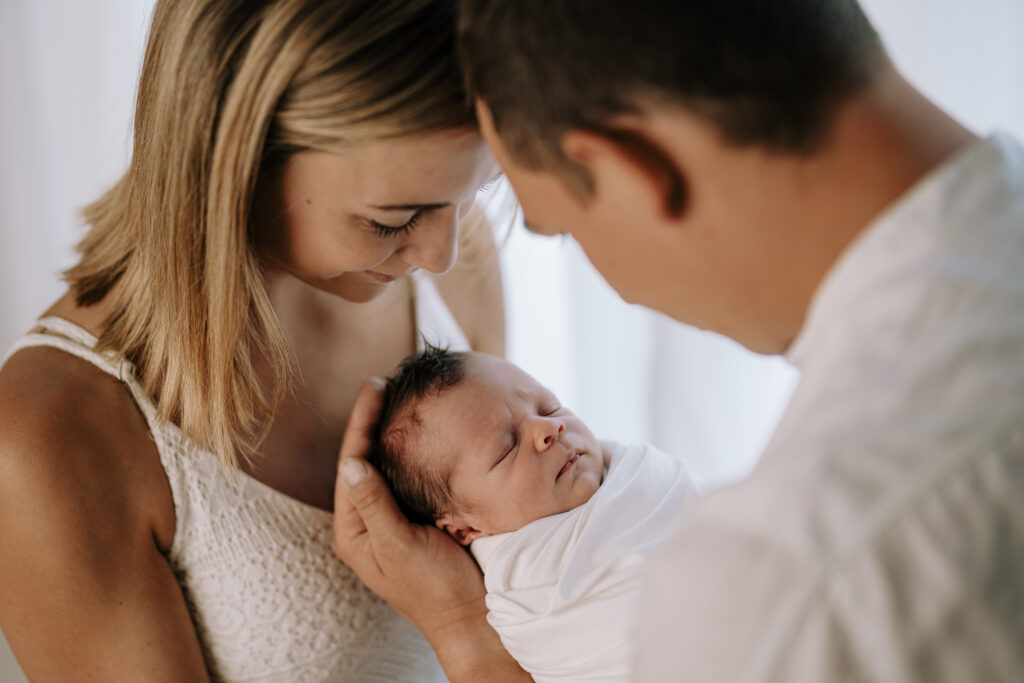 Eltern blicken liebevoll auf ihr Neugeborenes im Arm der Mama – Sabrina Dötzl Fotografie Hollabrunn