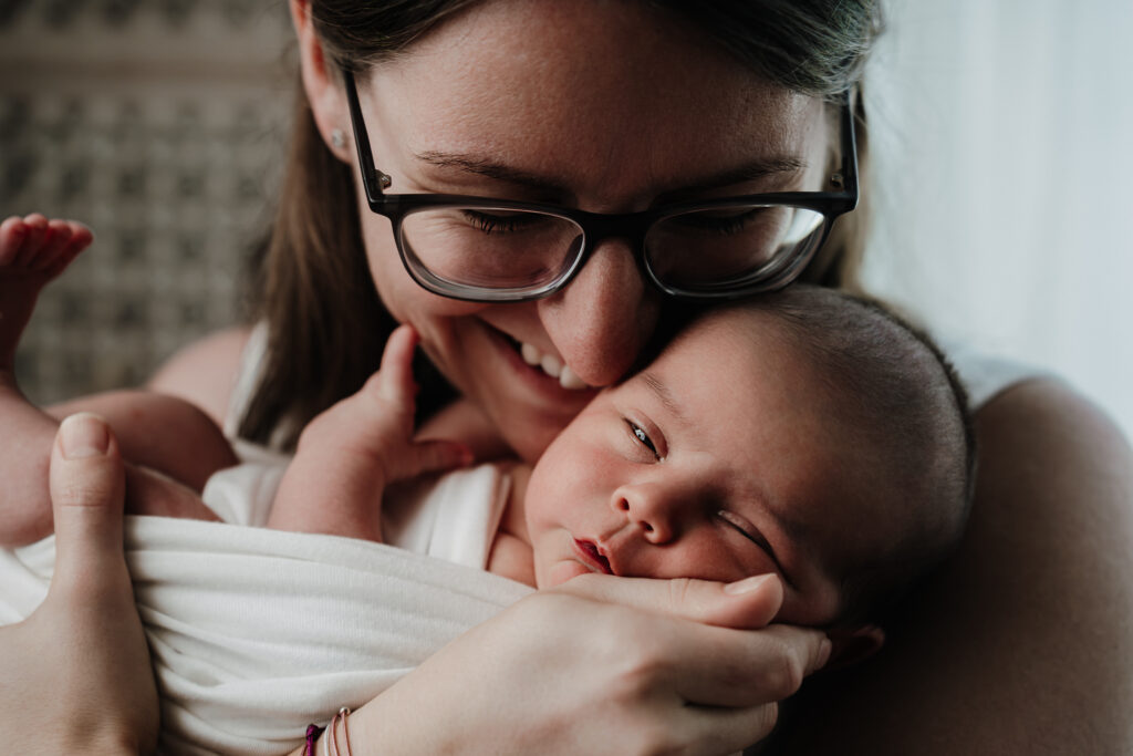 Mama mit Brille kuschelt ihr Neugeborenes an die Wange – Sabrina Dötzl Fotografie Hollabrunn