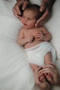 Neugeborenes von oben, gehalten von den Händen von Mama und Papa – Sabrina Dötzl Fotografie Hollabrunn
