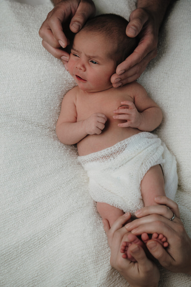 Neugeborenes von oben, gehalten von den Händen von Mama und Papa – Sabrina Dötzl Fotografie Hollabrunn